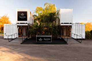 large green tree inbetween risers and storage boxes with a sign out front. pop up shops