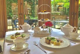 white tea cups, plates, assorted foods in a hotel overlooking trees