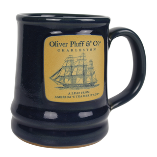 close up shot of a blue ceramic mug with the oliver pluff logo and ship on the front