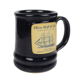close up view of dark blue ceramic mug with oliver pluff logo and ship emblem