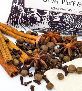 black and white tea pouch with cinnamon sticks, cloves, allspice, star anise and a tea bag scattered in front