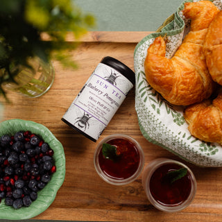 blueberry pomegranate tea tin on tray surrounded by breakfast pastries and fruit