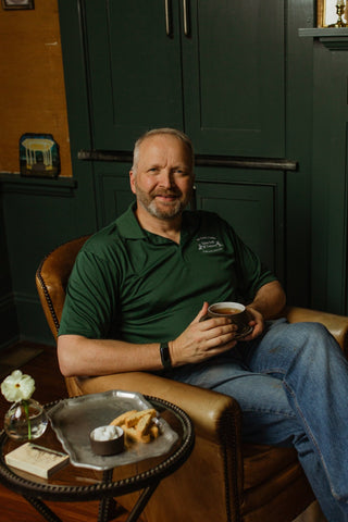 man sitting in leather chair holding cup of tea