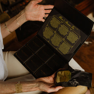 woman holding open and showing interior view of oliver's reserve gift box descriptions of each tea on the lid