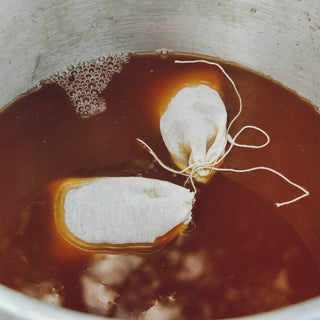 zoomed in view of brown tea with bubbles and two white tea bags floating