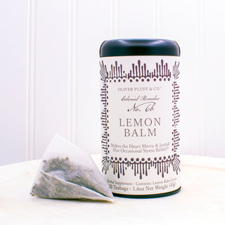 black tea tin with dark purple pattern on label sitting beside white mesh tag bag on white plate