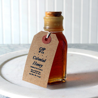 small rectangular glass honey jar with cork sitting on white plate