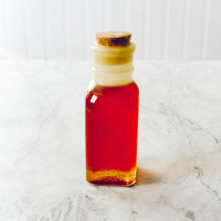 small rectangular glass honey jar with cork sitting on white plate