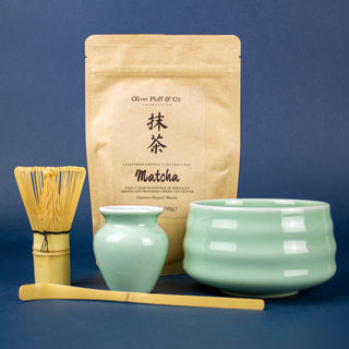 brown tea bag, brown matcha whisk, green ceramic tea pots with blue background