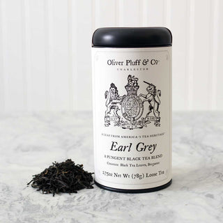 black tea tin standing beside a pile of loose leaf tea on a white countertop