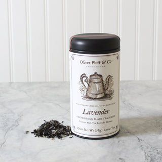 black tea tin with old timey tea kettle on label and pile of loose leaf tin beside it on marble counter