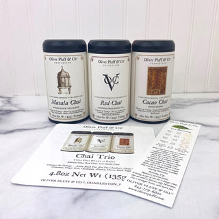 three black tea tins in a row with a bookmark and paper photo of them all sitting on kitchen counter