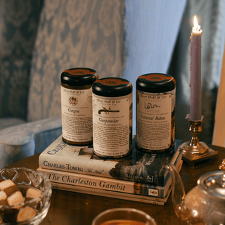 three tea tins sitting on top of books on side table in front of a blue chair