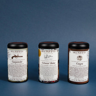 Three cylindrical tea canisters with labels on a blue background