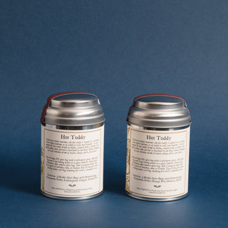 brewing instructions on backside of two small silver tea tins with yellow flowery graphic