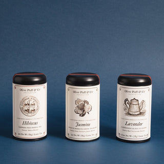 three black tea tins in a row against blue background