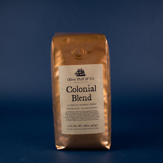 one orange-golden coffee bag with black and white sailboat on label sitting on blue back drop