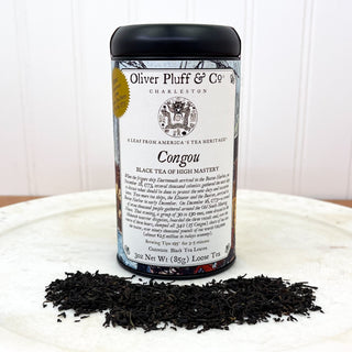 Tin of Oliver Pluff Congou Tea with tea sprinkled in front of it on white backgrounds