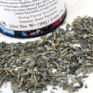 close up view of loose leaf tea sprinkled in front of black tea tin  on white counter 