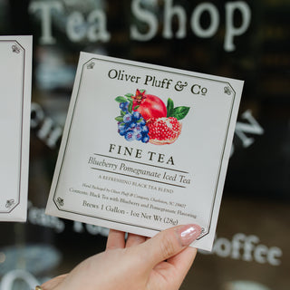 hand holding blueberry pomegranate iced tea packet in front of shop window