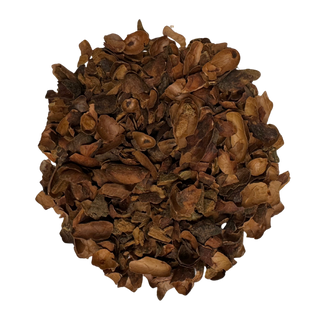 Pile of roasted brown cacao shells and cinnamon pieces on a white background
