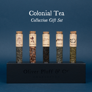 5 tubes of green, herbal or black teas with labels in black rectangular stand on blue background