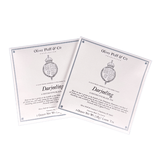 Two packages of Oliver Pluff & Co Darjeeling tea on a green background