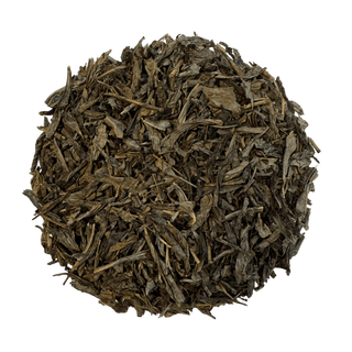 A circular pile of loose-leaf tea leaves, showing a mix of dark brown and olive-green dried foliage, isolated on a solid green background.