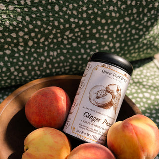 Oliver Pluff & Co ginger peach tea canister with peaches on a green patterned fabric background
