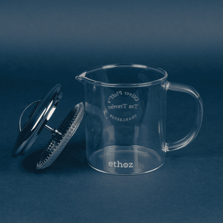 Clear glass tea infuser with handle on a dark blue background