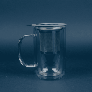 clear glass mug that reads with stainless steel brewing basket resting inside and grey lid on blue background