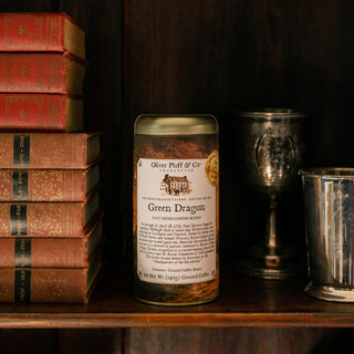 Can of 'Green Dragon' coffee blend on a shelf with books and cups