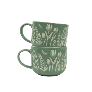 Two green mugs with floral patterns stacked on a white background
