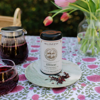 Herbal tea packaging with a glass of tea and flowers on a patterned tablecloth