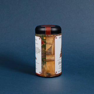 tea tin with black lid and decorative label featuring a christmas tree with ornaments on blue background