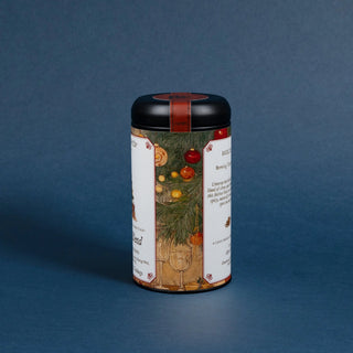 tea tin with black lid and decorative label featuring a christmas tree with ornaments on blue background