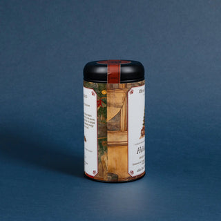 tea tin with black lid and decorative label featuring a christmas tree with ornaments on blue background
