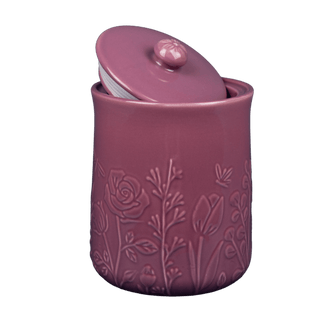 Pink ceramic jar with floral embossing and a matching pink lid on a transparent background
