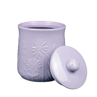 light purple stoneware storage jar with embossed floral design and lid with handle leaned against its side