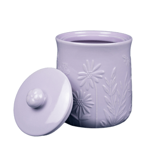 light purple stoneware storage jar with embossed floral design and lid with handle leaned against its side