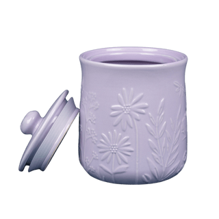 light purple stoneware storage jar with embossed floral design and lid with handle leaned against its side