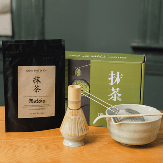 Oliver Pluff Matcha Gift Set with organic matcha, bamboo whisk, ceramic matcha bowl, scoop, and sifter arranged on a wooden table