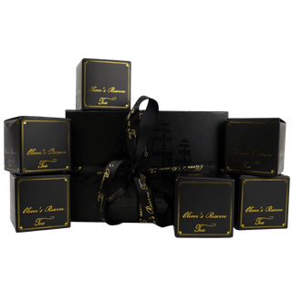 black gift box on white background tied with ribbon that reads 'oliver's reserve'. 6 small black boxes surround it