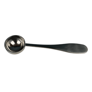 A stainless steel measuring spoon with a long handle, shown against a solid green background. The handle has a faint, partially legible brand engraving that appears to read 'Oliver Pluff'.