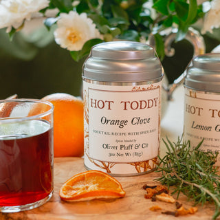 toddy tin sitting on cutting board surrounded by herbs and spices