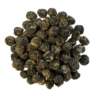 Pile of dark rolled black tea leaves on a white background
