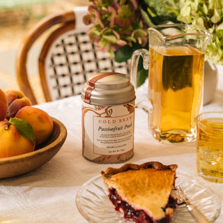 tea tin on tabletop surrounded by flowers and pie