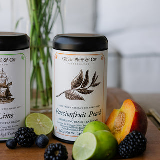 Tea canisters with fruit and berries on a wooden surface, featuring Oliver Pluff & Co branding.