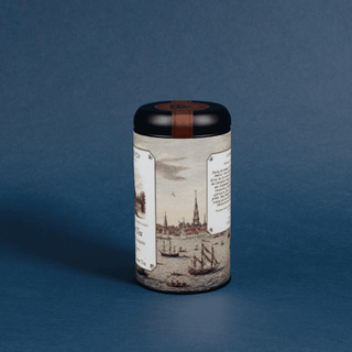 Cylindrical container with a decorative label featuring maritime scenes on a blue background