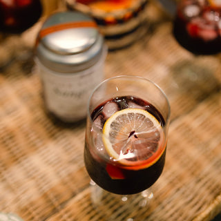 Glass of sangria with a lemon slice on a wooden table next to tin